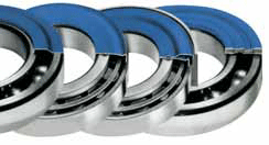 Szerokie ujęcie wnętrza magazynu DAKAM, akcentujące dużą dostępność. Na pierwszym planie, na regale lub stole, leżą pudełka i opakowania z pierścieniami NILOS r&oacute;żnych rozmiar&oacute;w. Opakowania są opisane kodami i średnicami, co symbolizuje pełną dostępność rozmiar&oacute;wki "od ręki". Pracownik DAKAM w firmowej odzieży dokonuje weryfikacji kodu na jednym z opakowań pierścieni. Zdjęcie symbolizuje szybką logistykę i gotowość DAKAM do dostarczenia specjalistycznych, precyzyjnych pierścieni uszczelniających NILOS.